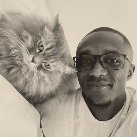 Umaru Biango at home, with his cat beside him.